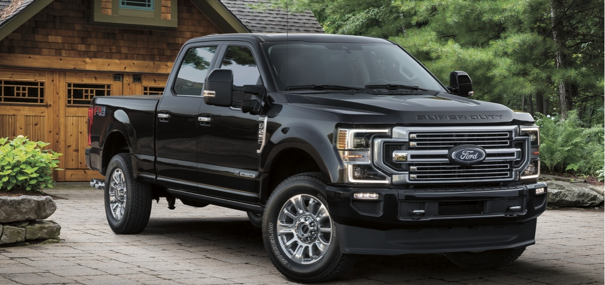 A black 2022 Ford F-250 Super Duty parked in front of a garage, with trees in the background.