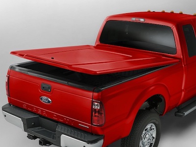 Rear-view of a red 2019 Ford F-350 Super Duty, with a hard-top tonneau cover opened across the bed.