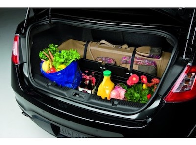 A Ford cargo organizer placed in an open trunk and holding various groceries, plants, and luggage.