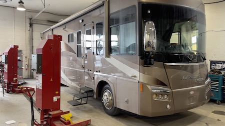 A brown Ford-chassis motorhome parked in the Skaha Ford repair facility, with various diagnostic tools placed beside it.