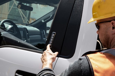 A construction working using the Securi-Code keypad on the side of a white 2022 Ford F-550 XLT.