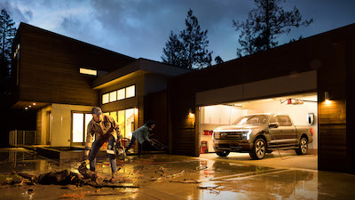<a href="https://clients.webstager.com/skahaford.com/2022-ford-f150-lightning-truck-in-canada/"><img src="images/upload/October_2021/Commercial_News/7-2022-Ford-F-150-Lightning-Platinum-backup-power-penticton-bc.jpg"alt="A 2022 Ford F-150 Lightning plugged into a house to be used as backup power after a storm took out the grid; a man and woman clean up fallen trees on the driveway"/></a>